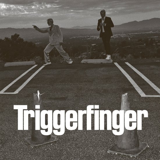 Deux hommes en costume sur un parking avec le texte 'Triggerfinger'.