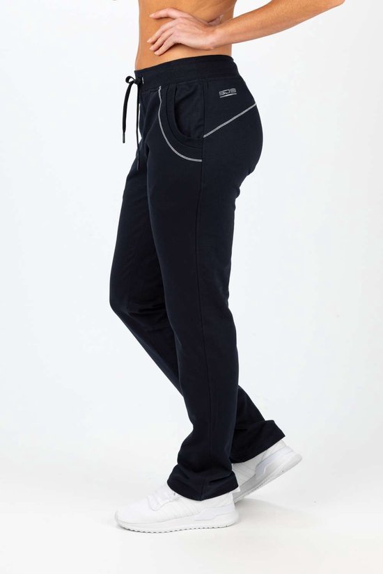 Vrouw in een donkerblauwe joggingbroek met witte sierstiksels en sneakers.