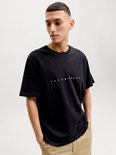 Model draagt een zwarte Jack & Jones t-shirt met witte tekst.