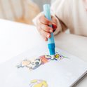 Close-up van een kinderhand die met een blauwe pen in een schetsboek met illustraties tekent.