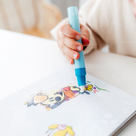 Close-up van een kinderhand die met een blauwe pen in een schetsboek met illustraties tekent.