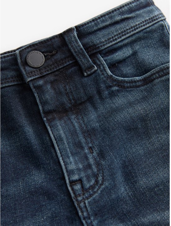 Detail van de voorkant van een donkerblauwe spijkerbroek, met knoop en knoopsluiting.