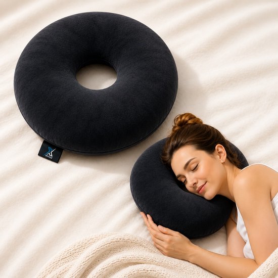 Een vrouw slaapt op een bed met een zwart donut kussen, een ander zwart donut kussen ligt ernaast.