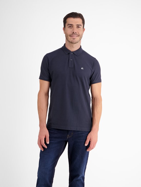 Man, van voren, draagt een marineblauw piqué poloshirt met korte mouwen en een klein logo op de borst.