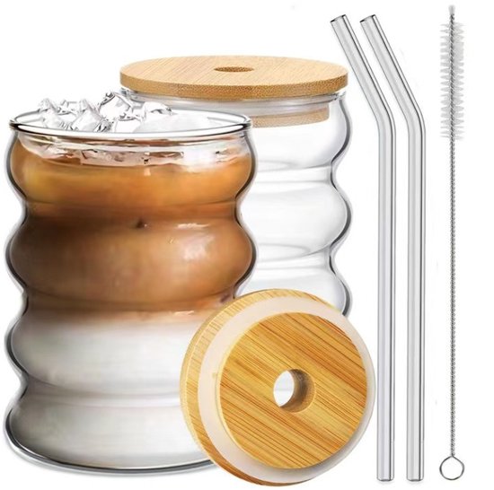 Verre en verre avec du thé glacé, un couvercle en bambou avec une paille et une brosse de nettoyage.