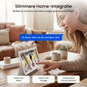 Vrouw bedient camera met spraakopdracht 'Hi Alexa, laat me de voordeur zien' op tablet, toont beelden van buiten.