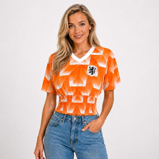 Vrouw met lang blond haar in een oranje retro voetbalshirt met wit kraagje en blauwe spijkerbroek.