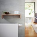 Netatmo slimme thermostaatknop op witte radiator. In de achtergrond een plank met thermostaat en zithoek.
