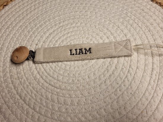 Crèmekleurig fopspeenkoord met de naam 'LIAM' geborduurd in zwart. Met houten clip.