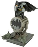 Batman-figuur op een schijnwerper met Bat-logo, omringd door gargoyle-versieringen.