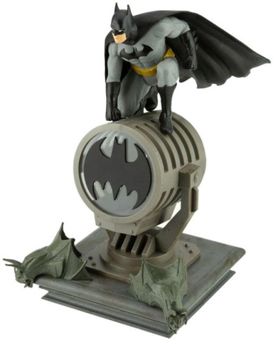 Batman-figuur op een schijnwerper met Bat-logo, omringd door gargoyle-versieringen.