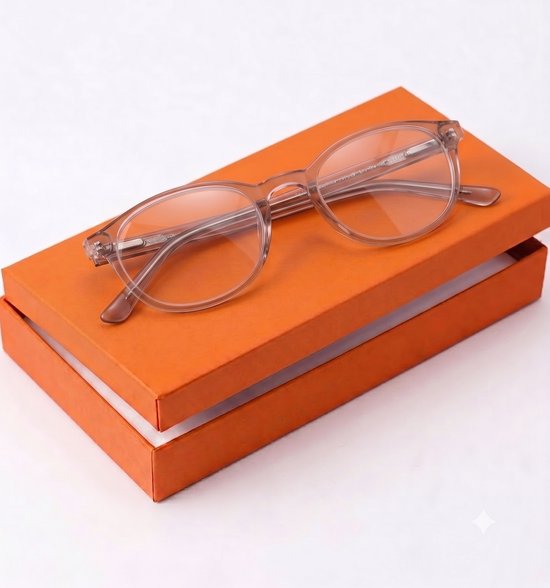 Lunettes de lecture rose translucide sur une boîte orange.