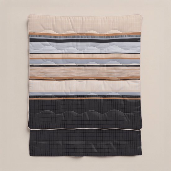 Een platliggend dekbed met horizontale strepen in beige, wit, grijs, bruin en zwart, met een geruit patroon aan de onderkant.