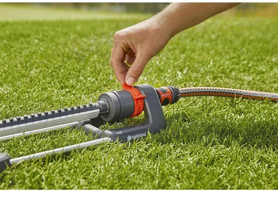 Hand sluit oranje deel aan op de GARDENA zwenksproeier.