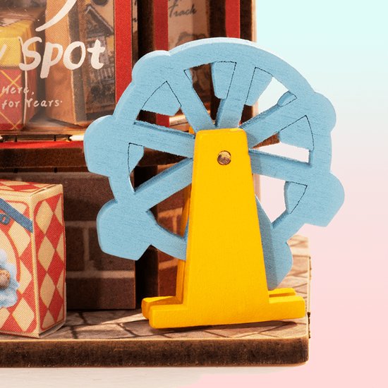 Miniatuur blauwe reuzenrad met een gele standaard, naast een speelgoedwinkel display.