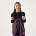 Meisje met lang bruin haar, draagt een zwarte top en paarse bretelbroek. Logo op de banden.