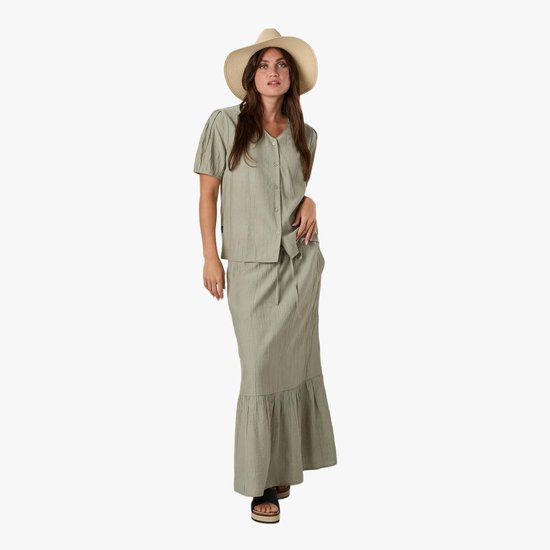 Model in een lichtgroene crinkle blouse met korte mouwen, lange crinkle rok en strooien hoed.