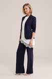 Dames donkerblauwe blazer gedragen met een witte top met kanten details en een donkerblauwe broek.