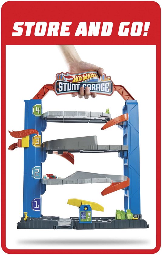 Een hand houdt een blauwe Hot Wheels Stunt Garage speelgoedauto garage omhoog met vier verdiepingen en oranje en grijze hellingen.