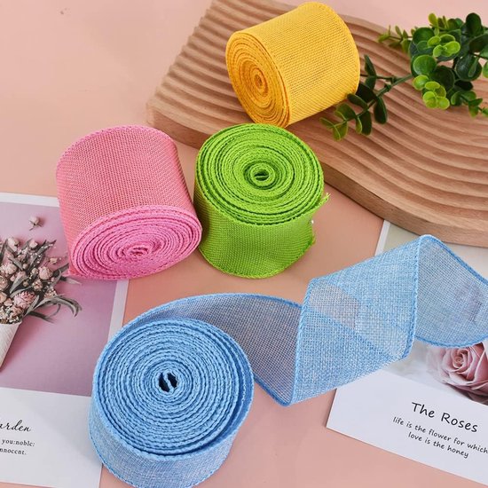 Vier rollen lint in de kleuren blauw, groen, roze en geel. De blauwe is uitgerold op een witte achtergrond met tekst.