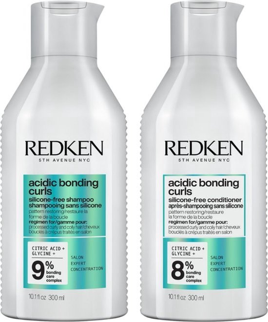 Deux bouteilles blanches Redken avec étiquettes vertes : shampooing et après-shampooing pour cheveux bouclés.