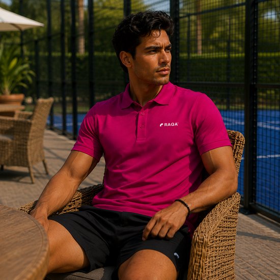 Man in een roze poloshirt met korte mouwen en zwart sportbroekje, zittend.