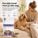 Vrouw die een goudkleurige doodle hond aait, naast een verpakking 'Probiotica + Prebiotica voor Honden' en een bakje brokjes.