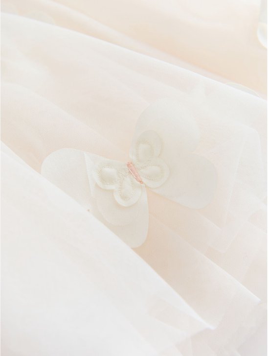 Detail van crèmekleurige tule jurk met een applicatie van een crèmekleurige vlinder.