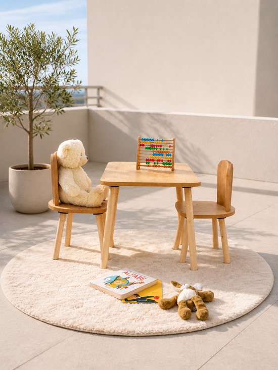 Houten kindertafel met twee stoelen op een rond vloerkleed, met een teddybeer en een boek.