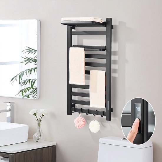Moderne zwarte elektrische handdoekradiator, aan de muur gemonteerd in een badkamer. Twee witte handdoeken hangen aan de stangen. Een digitaal display toont '70'.