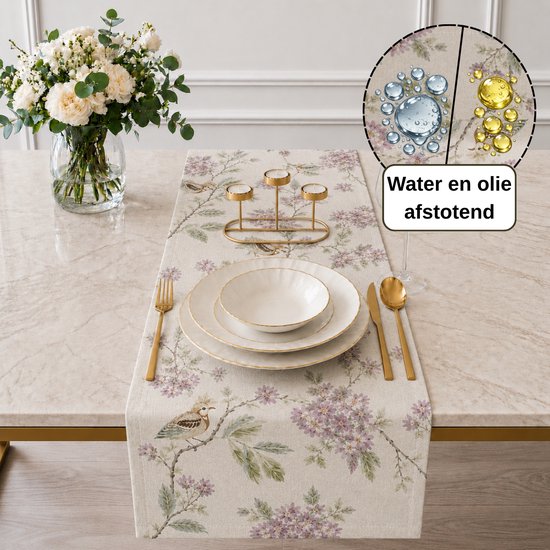 Crèmekleurige tafelloper met bloemen- en vogelprint, gedekt op een marmeren tafel. Water- en olieafstotend.