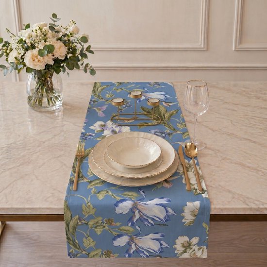Blauwe tafelloper met bloemen- en vogelprint op gedekte tafel.