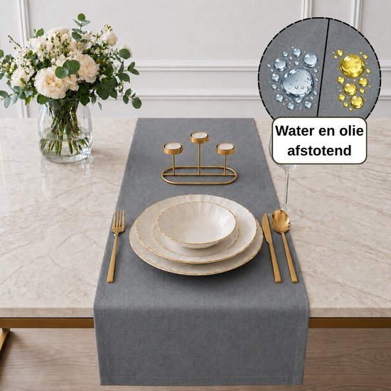 Een parelgrijze tafelloper van Tavas met gouden bestek, borden en kandelaar.