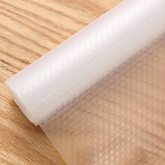 Tapis antidérapant transparent avec relief circulaire, enroulé sur une surface en bois.