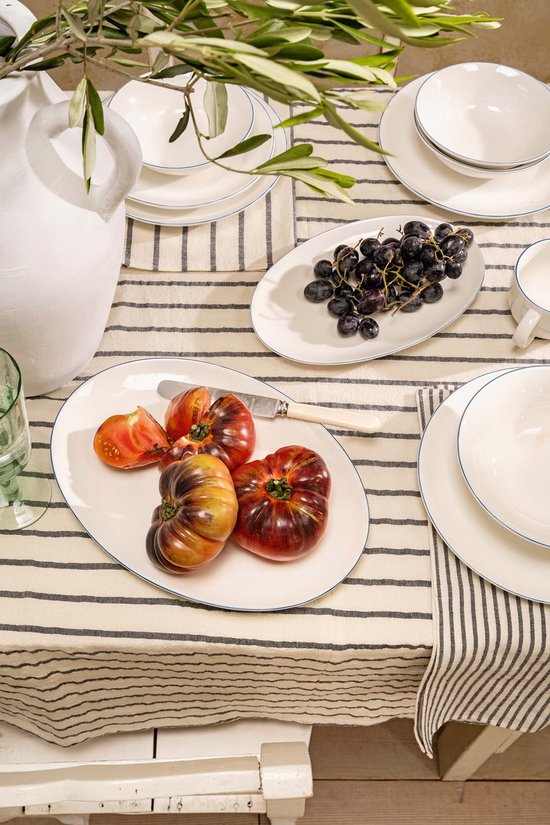 Gedekte tafel met gestreept tafelkleed, witte kan met strepen, witte mok en bord met tomaten.