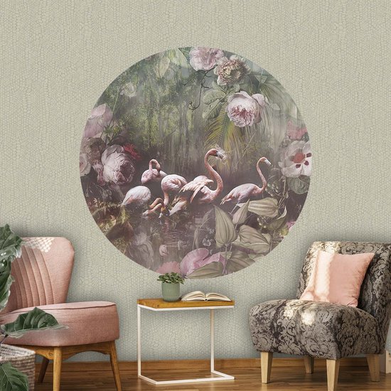 Een cirkelvormige wanddecoratie met roze flamingo's in een weelderige, donkere jungle met grote roze en rode bloemen. De achtergrond heeft een subtiel relief.