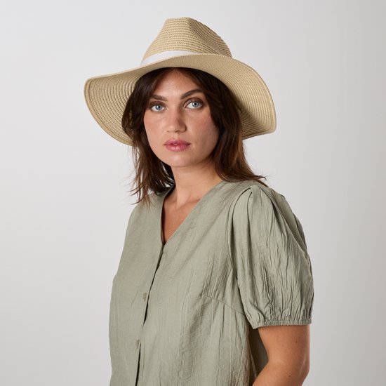 Close-up van een vrouw met blauwe ogen, draagt een lichtgroene blouse en een strooien hoed met wit lint.