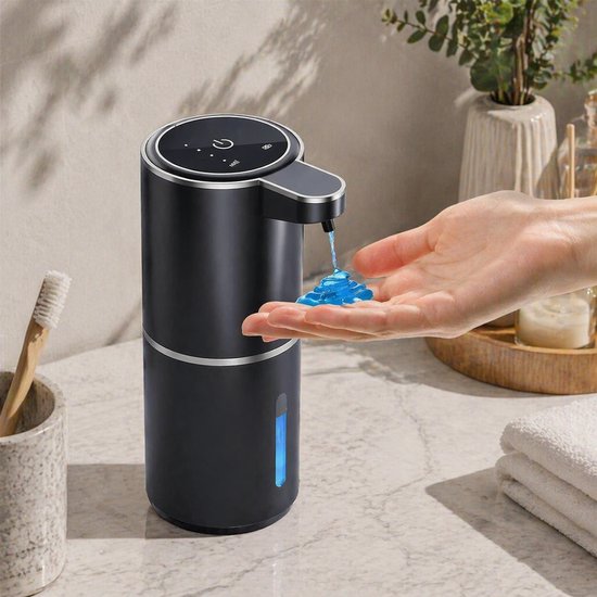Zwarte automatische zeepdispenser in gebruik in een badkamer, waarbij een hand schuim zeep opvangt.