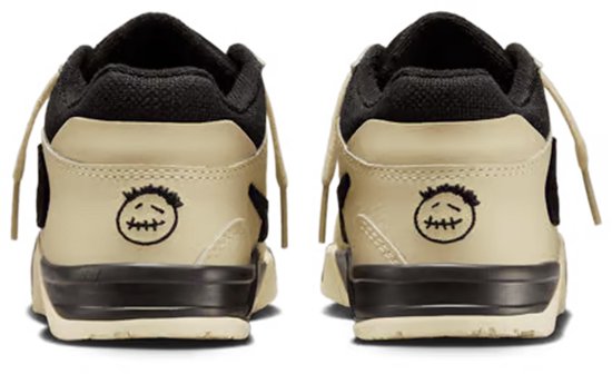 Achterkant van crèmekleurige kindersneakers met zwarte kraag en detail van een gezichtje.