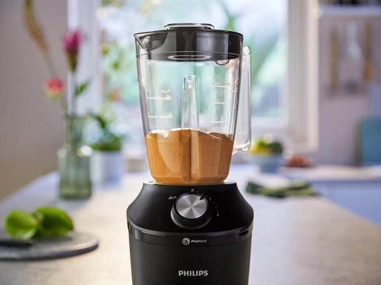 Zwarte Philips blender met een glazen kan gevuld met bruine smoothie.