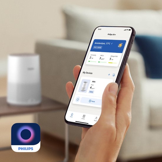 Smartphone affichant l'application Philips Air+ avec la qualité de l'air et le risque d'allergènes, un purificateur d'air en arrière-plan.