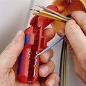 Handen gebruiken een rood en blauw ontmantelingsgereedschap om een blauwe kabel te strippen.