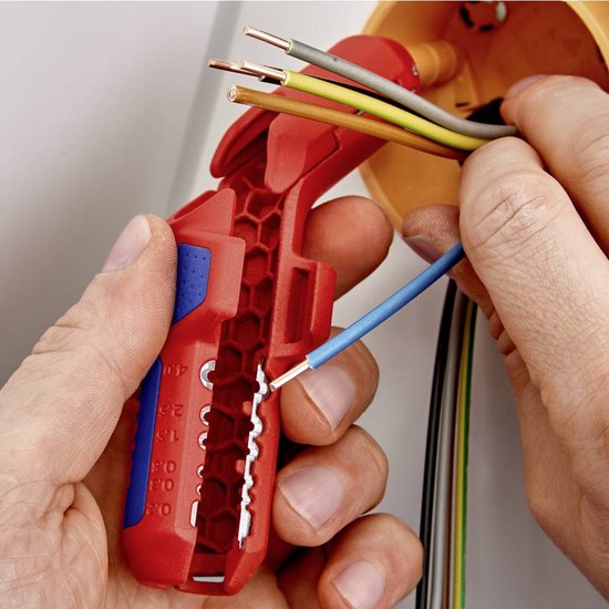 Handen gebruiken een rood en blauw ontmantelingsgereedschap om een blauwe kabel te strippen.
