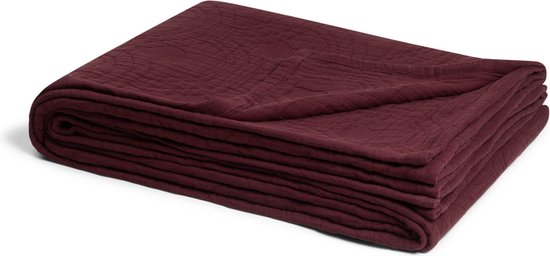 Gevouwen bordeauxrode sprei op een witte achtergrond