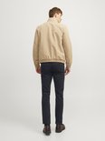 Man met beige bomberjack en zwarte chino, achterkant.