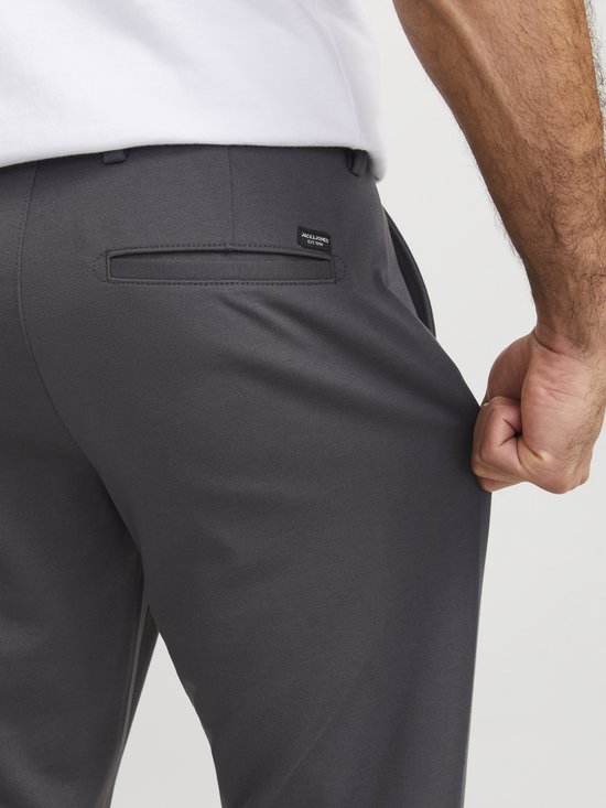 Close-up van de achterkant van een donkergrijze herenbroek met een zak en een zwart label van Jack & Jones.