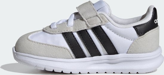 Witte kindersneaker met grijze suède overlays, zwarte Adidas-strepen en klittenbandsluiting.