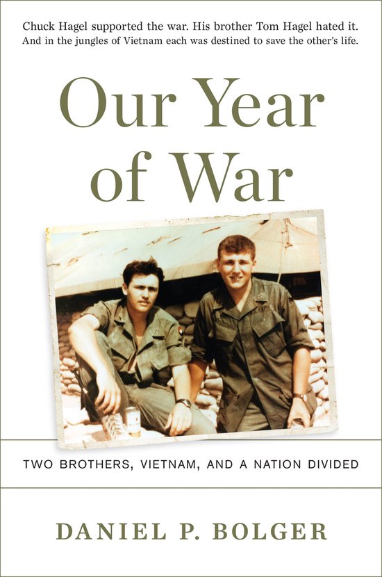 Twee jonge mannen in militaire uniformen, gezeten en staand, met een gebouw op de achtergrond. Titel: Our Year of War.
