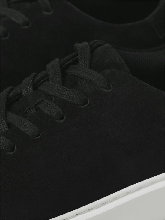 Close-up van de veters en zijkant van een zwarte suède sneaker.