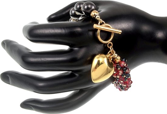 Gouden hartbedel, rode en zwarte kristallen bedel aan een armband met zwarte kralen, gedragen op een zwarte etalagehand.